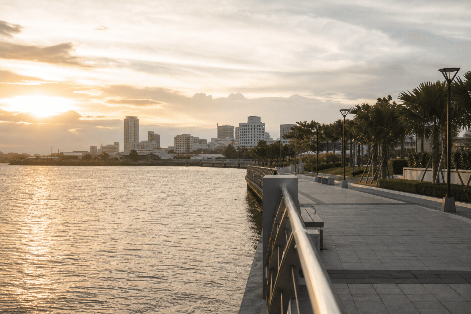 Iloilo City river esplanade at golden hour with the urban skyline in soft haze